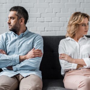 mad couple sitting on couch after quarrel and looking away