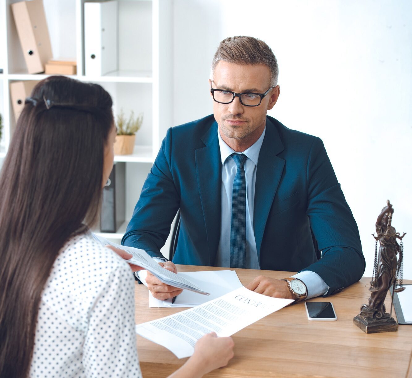 lawyer and client looking at each other while working with contract in office